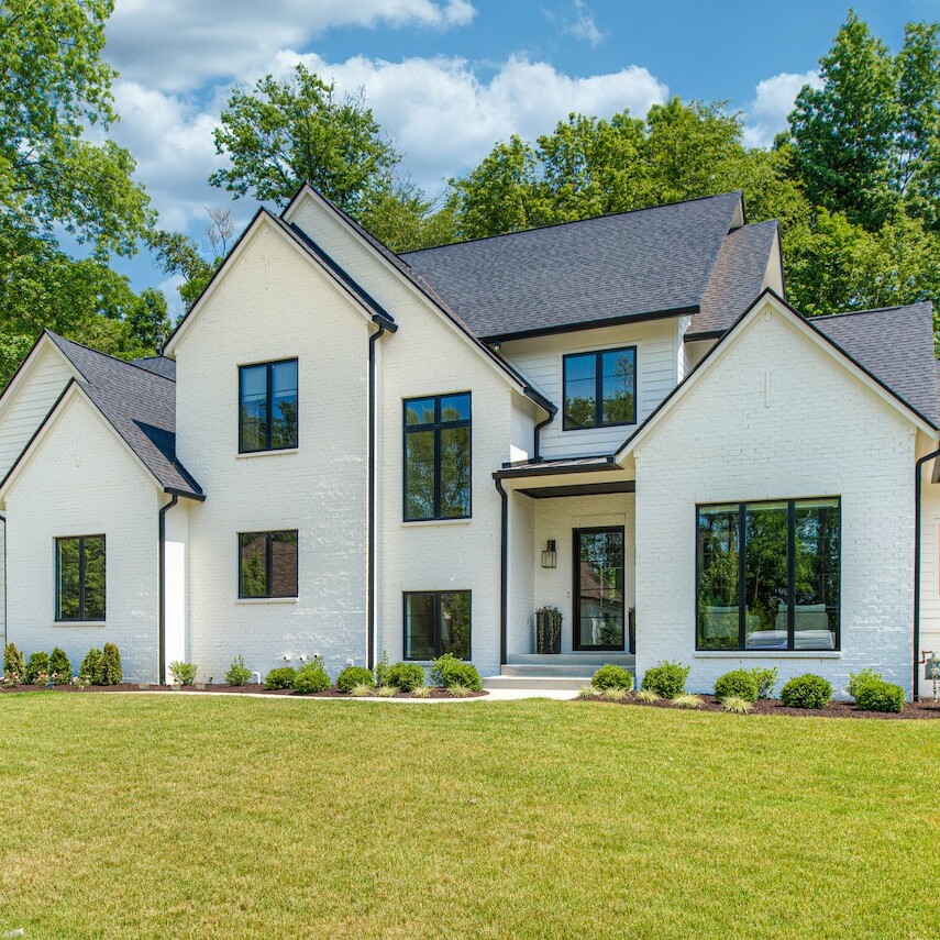 A white home with a green lawn and trees.