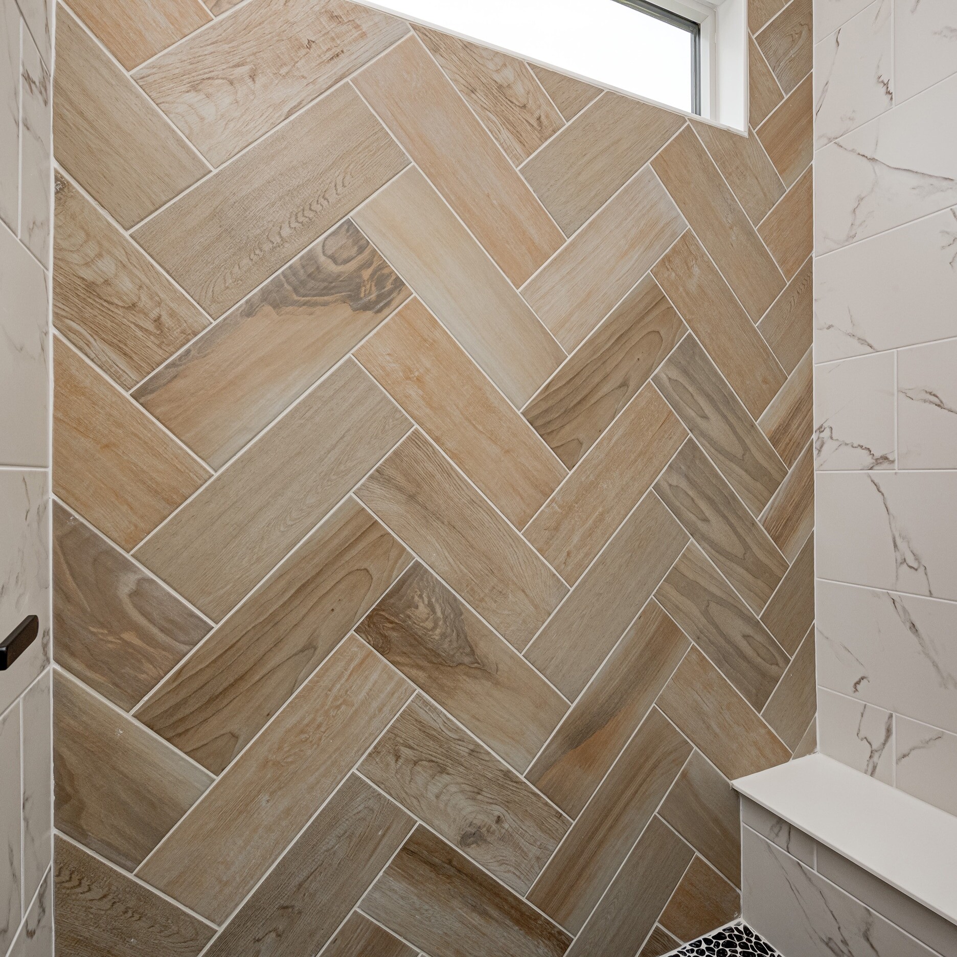 A herringbone tiled shower in a bathroom.