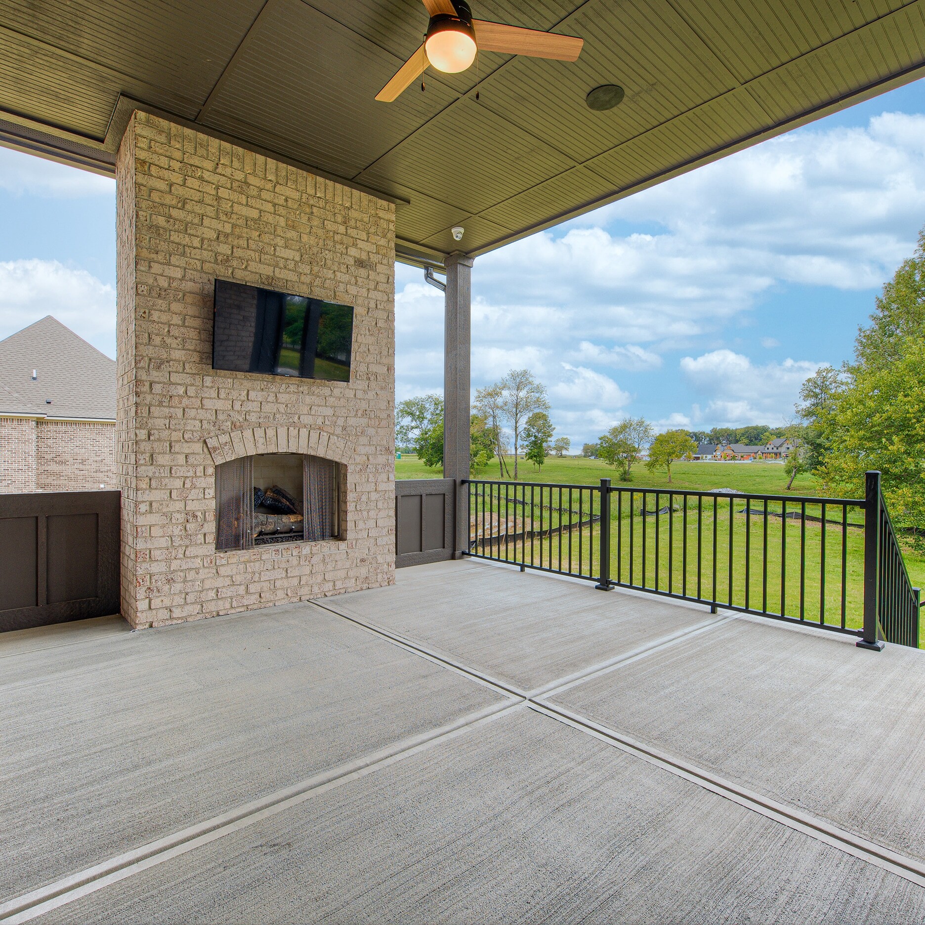 A covered patio with a fireplace and a tv.