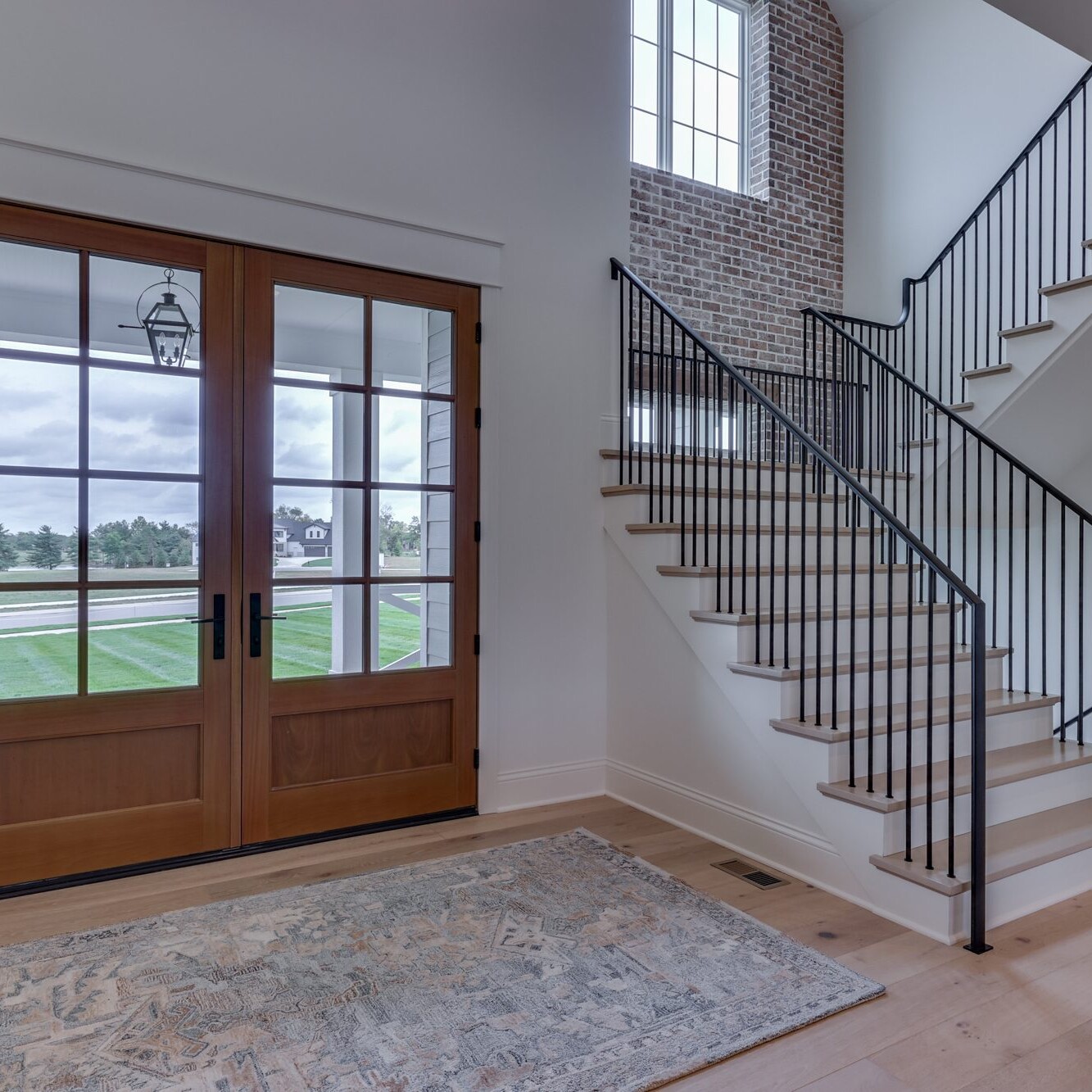 An entryway with a staircase and a rug.