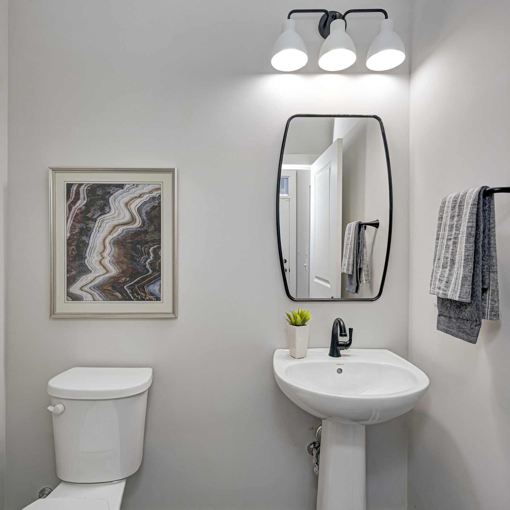 A custom bathroom in a new home with a toilet, sink and mirror.
