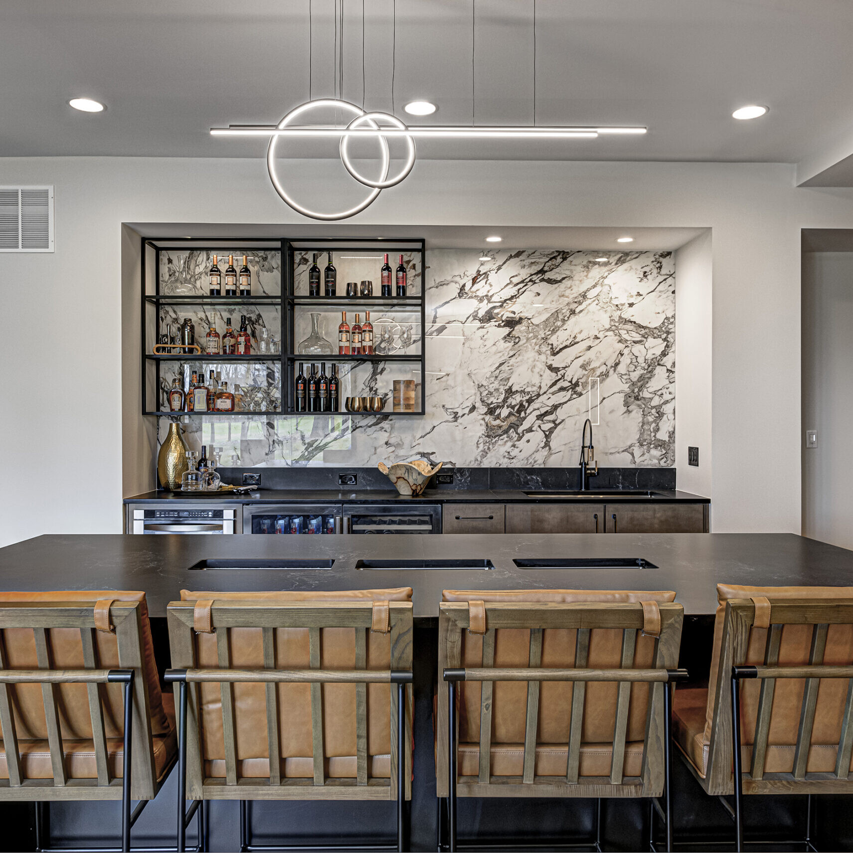 A kitchen with a marble counter top and stools.
