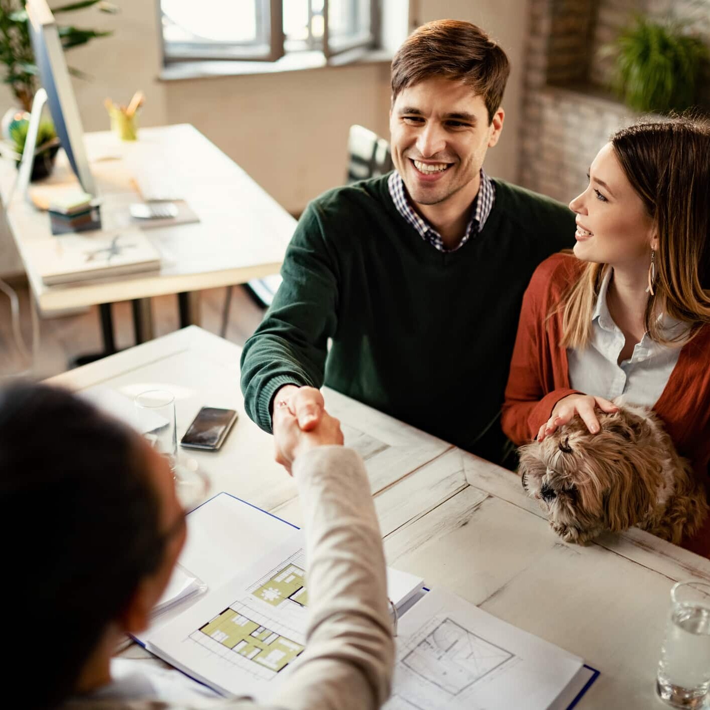 A man and woman shaking hands at a desk, discussing the construction of new custom homes in Westfield Indiana or Carmel Indiana.