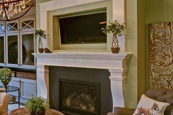 A living room with green walls and a chandelier, designed by a custom home builder in Carmel Indiana.